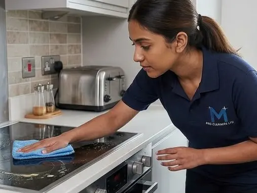 Team member wiping a glass stovetop clean with a blue cloth